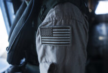 A CH-53E super stallion crew chief assigned to Marine Heavy Helicopter Squadron 463 "Pegasus," brandishes a coyote American flag patch on his uniform during a flight around Oahu, Hawaii, Sept. 23, 2014. The crew of the CH-53E conducted a single-point external lift of a decommissioned Navy A-4 skyhawk from Barber's Point to Joint Base Pearl Harbor-Hickam, Hawaii for the Wings Over the Pacific 2014 air show to be used as a static display. (U.S. Marine Corps Photo by Cpl. Matthew Callahan/ Released)