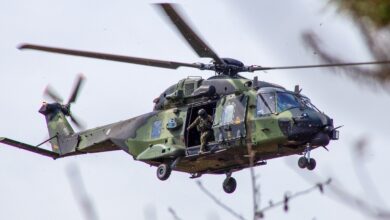 A soldier coming out of a Finnish NH90 helicopter flying mid-air